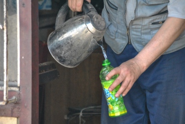 a man fills our water bottles with water he's freshly boiled in a kettle in the winter in Kyrgyzstan