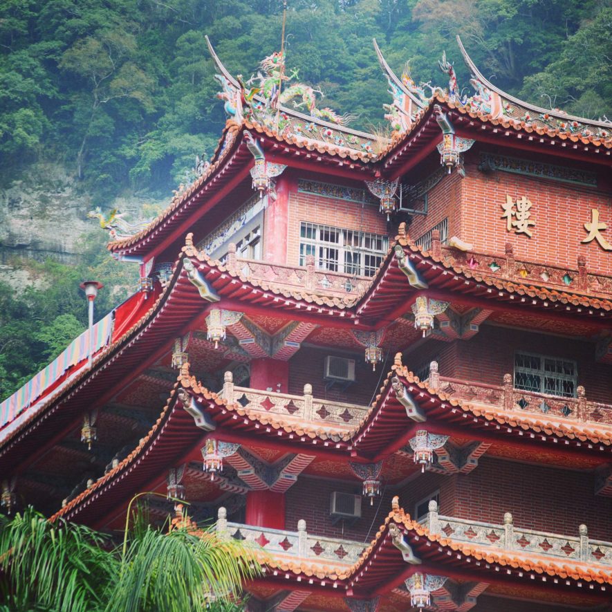 Chuan Hua Hall at Lion's Head Mountain nestled in lush green trees and built of bricks and ornate roofing 