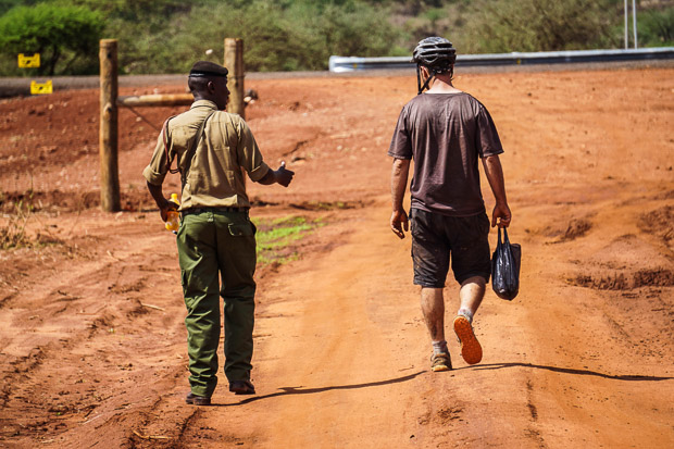 evan walking with a kenyan police officer outside Tsavo West National Park entrance
